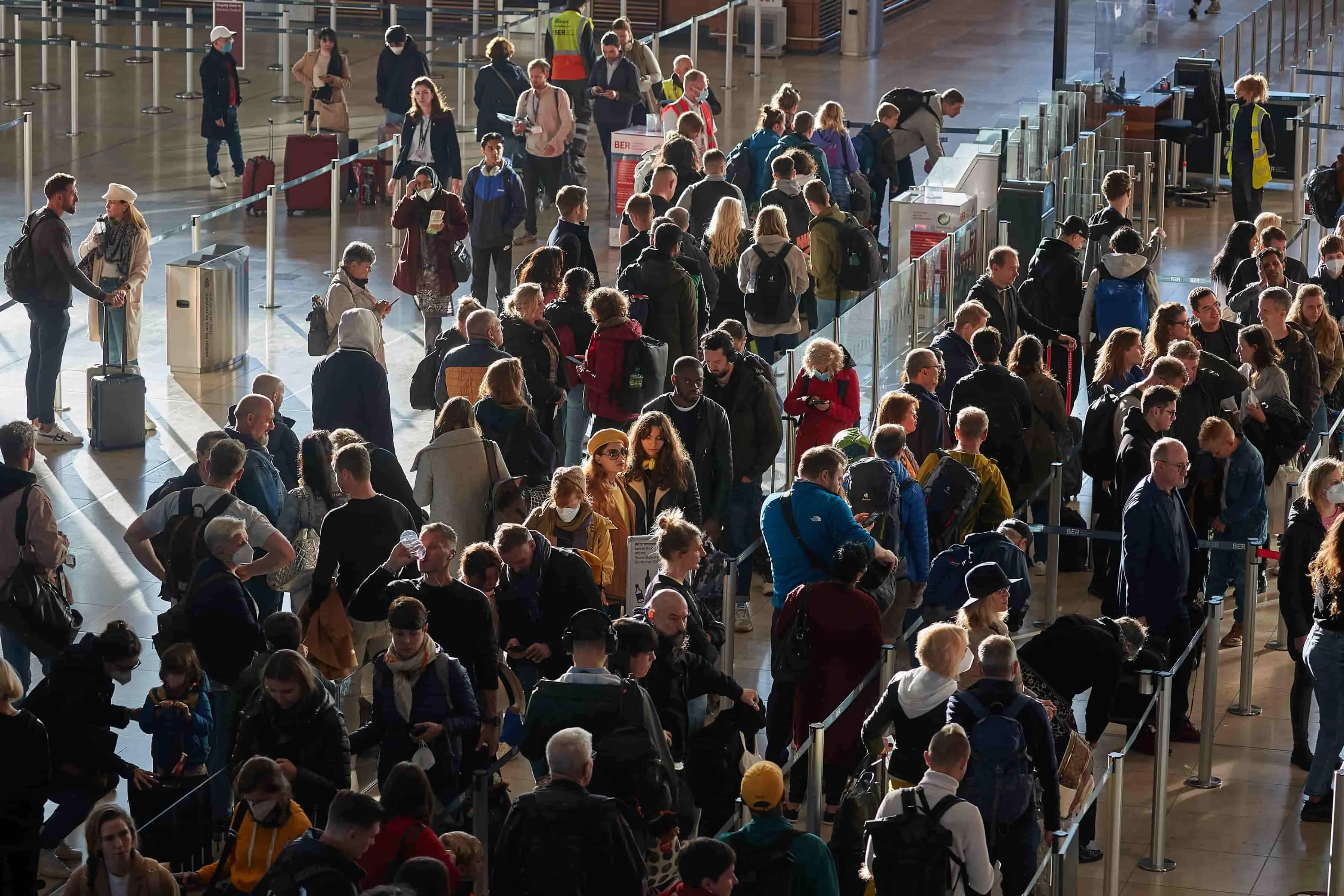 Crowded airport terminal with travelers snaking through long roped-off queues